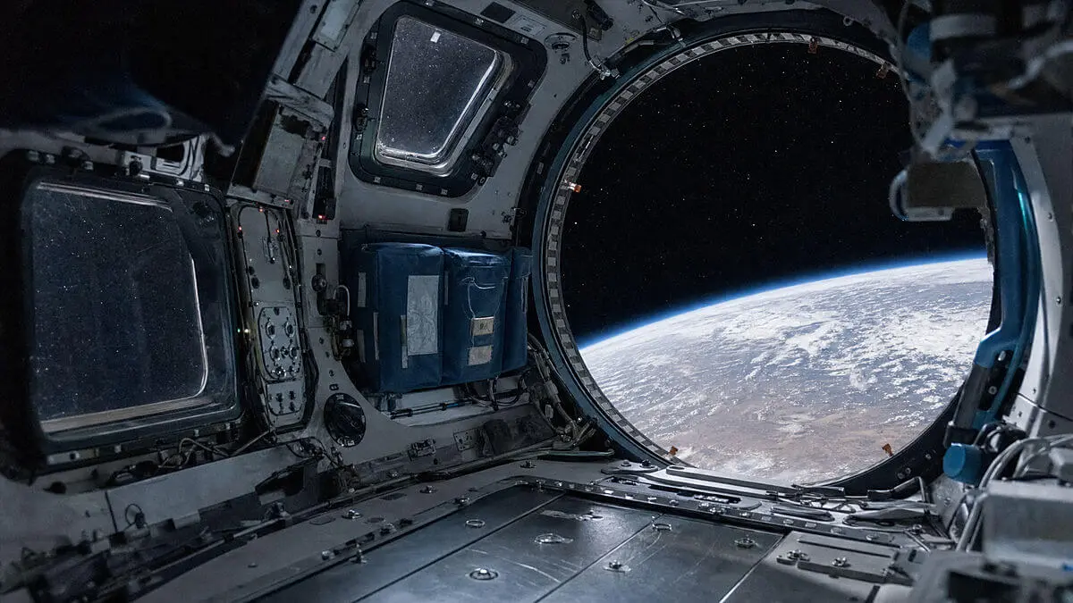 Side view of empty space cabin: windows with stars and distant Earth